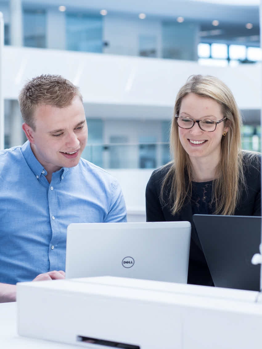 Two DSV employees a man and a woman looking at a computer screen in the office